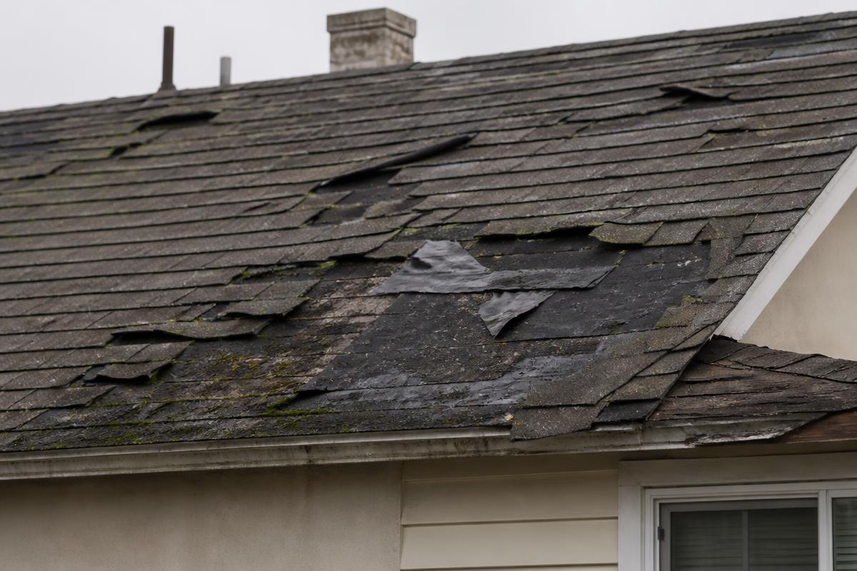 Before: storm damaged roof with cracked and missing shingles